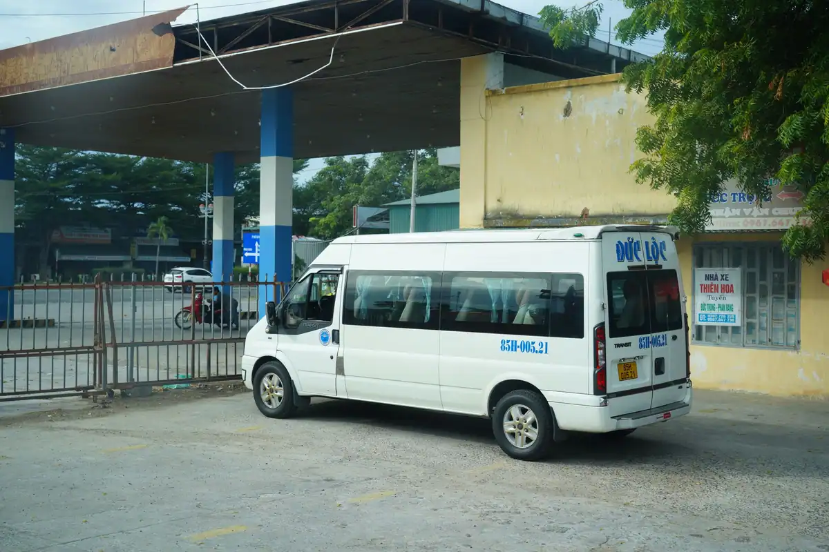 Microbuz alb parcat lângă o stație de autocare, pregătit pentru drumul spre alt oraș