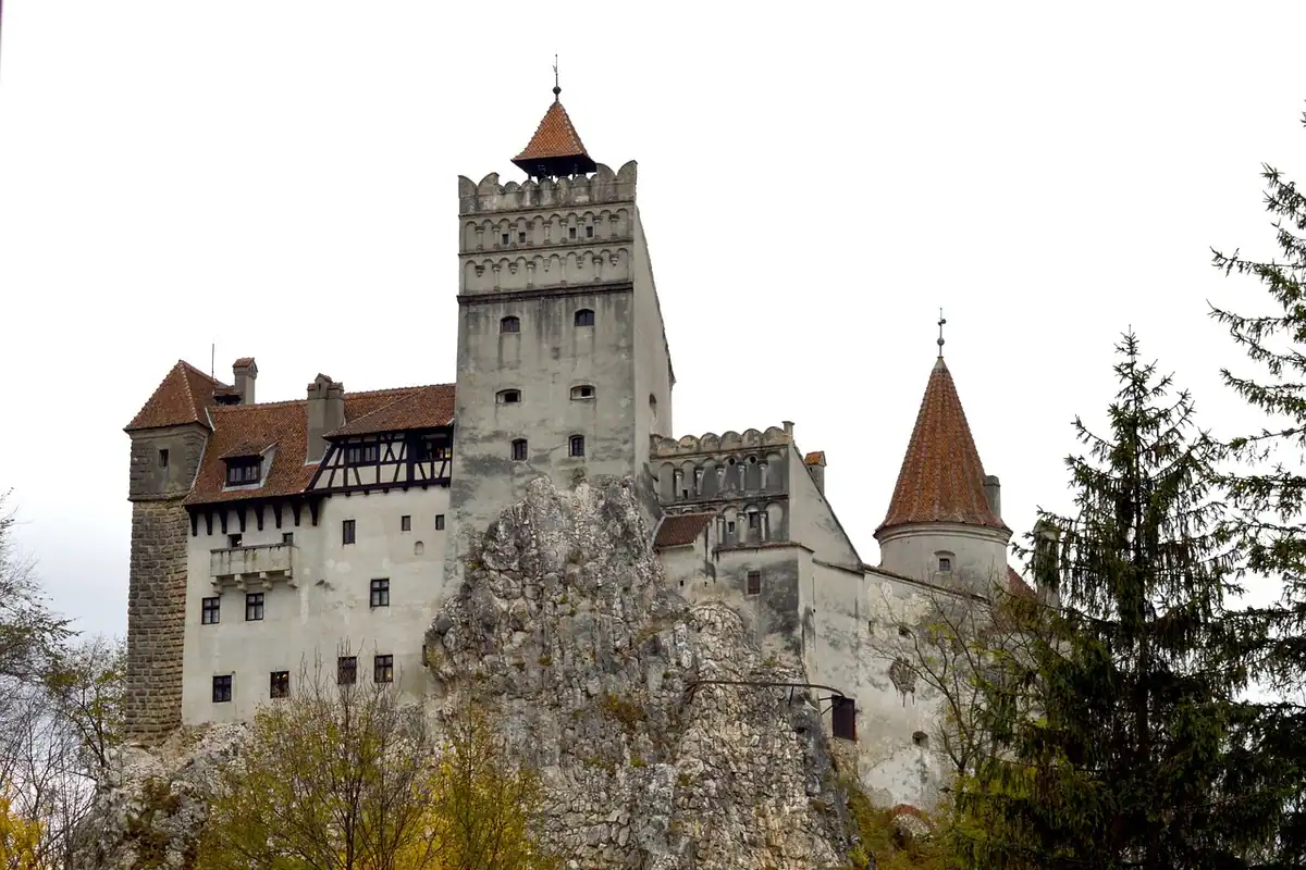 Castelul Bran, cocoțat pe stâncă, cu turnurile lui înconjurate de brazi