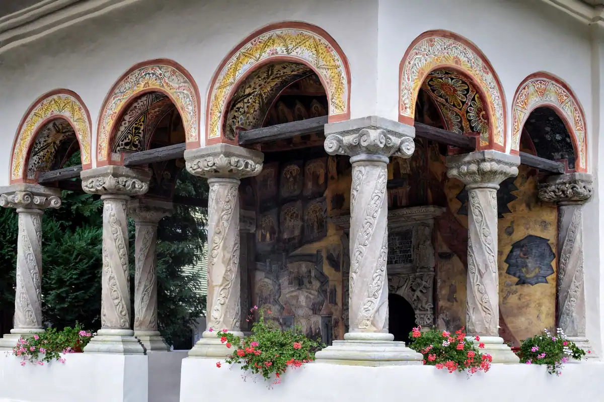 Arcade de piatră cu fresce și flori la o mănăstire pictată din Bucovina
