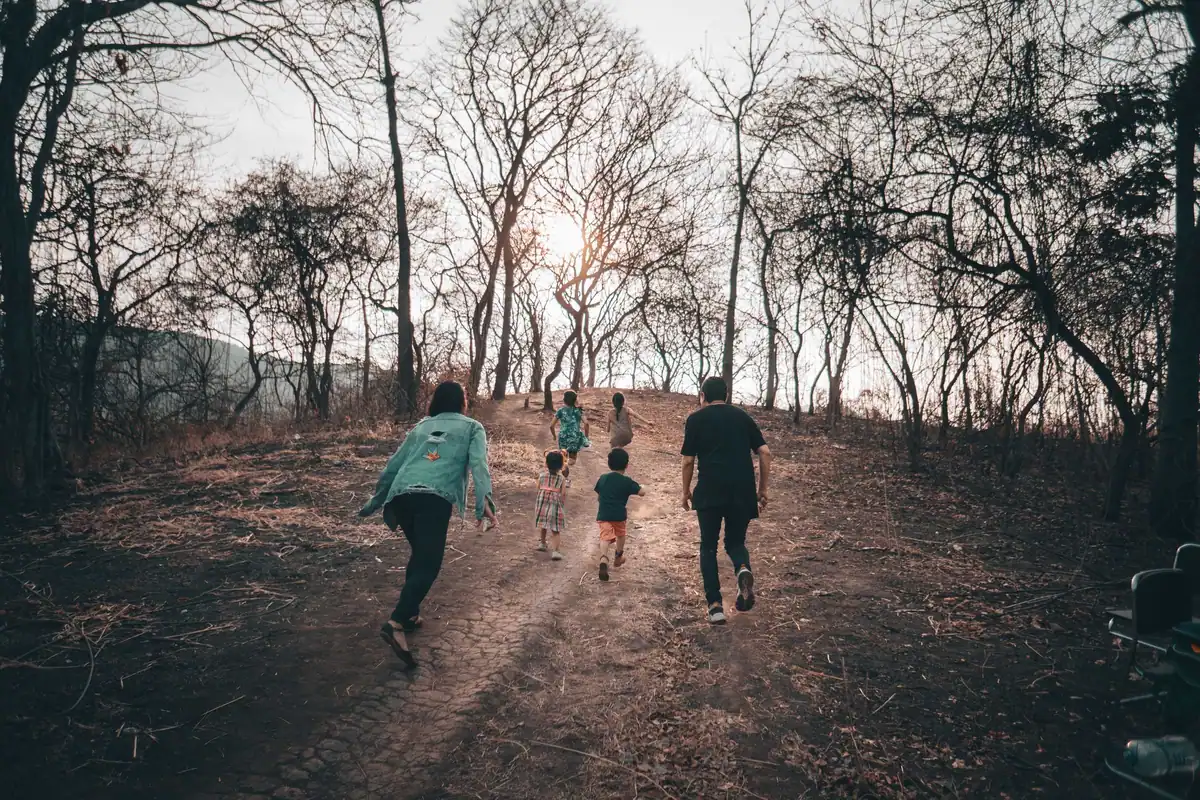 O familie merge la drumeție printr-o pădure toamnă, cu copiii alături