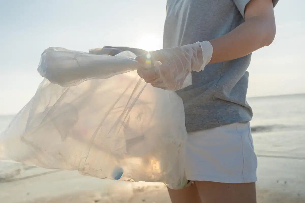 Voluntar care strânge sticle de plastic și deșeuri de pe jos, ca să lase natura curată