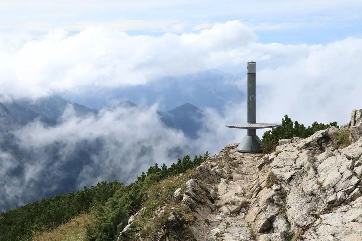 Ceață deasupra unei poteci montane, cu stânci și vârfuri pierdute în nori
