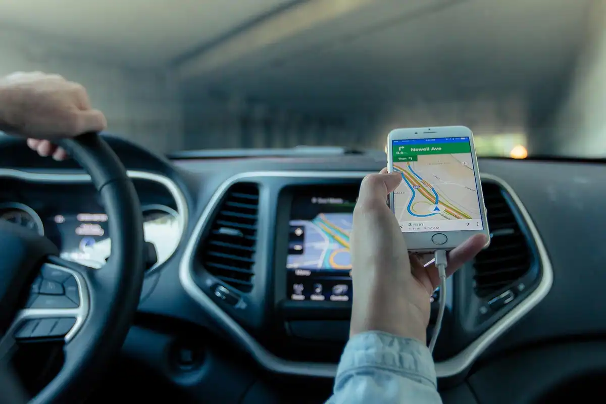 Telefon cu navigație GPS pe bordul unei mașini, afișând ruta pe hartă în timpul unei călătorii