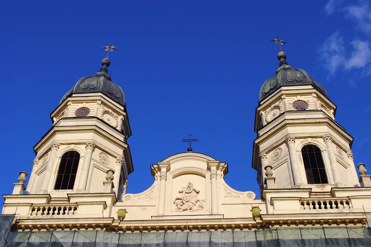 Două turnuri ale unei biserici cu cupole de culoare crem, pe fundal de cer albastru