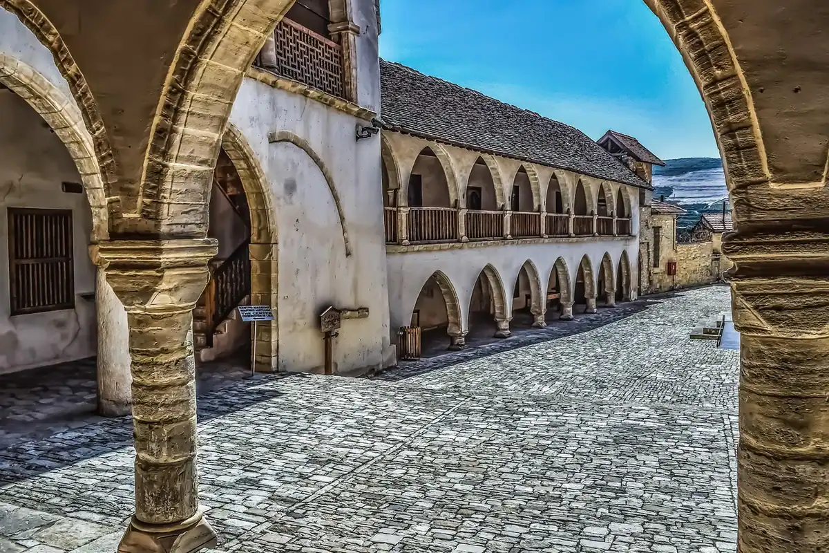Curte interioară de mănăstire ortodoxă, cu arcade de piatră și coloane în jurul unei galerii