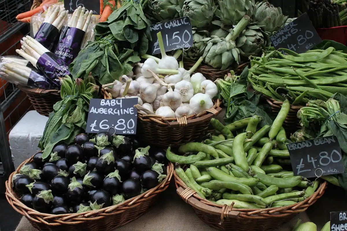 Tarabă dintr-o piață acoperită cu legume proaspete, vinete și etichete de preț la vedere