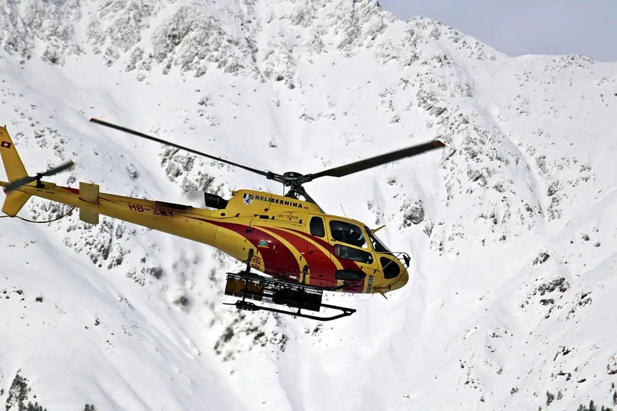 Elicopter de salvare care zboară deasupra munților înzăpeziți, într-o misiune de ajutor pe pantă