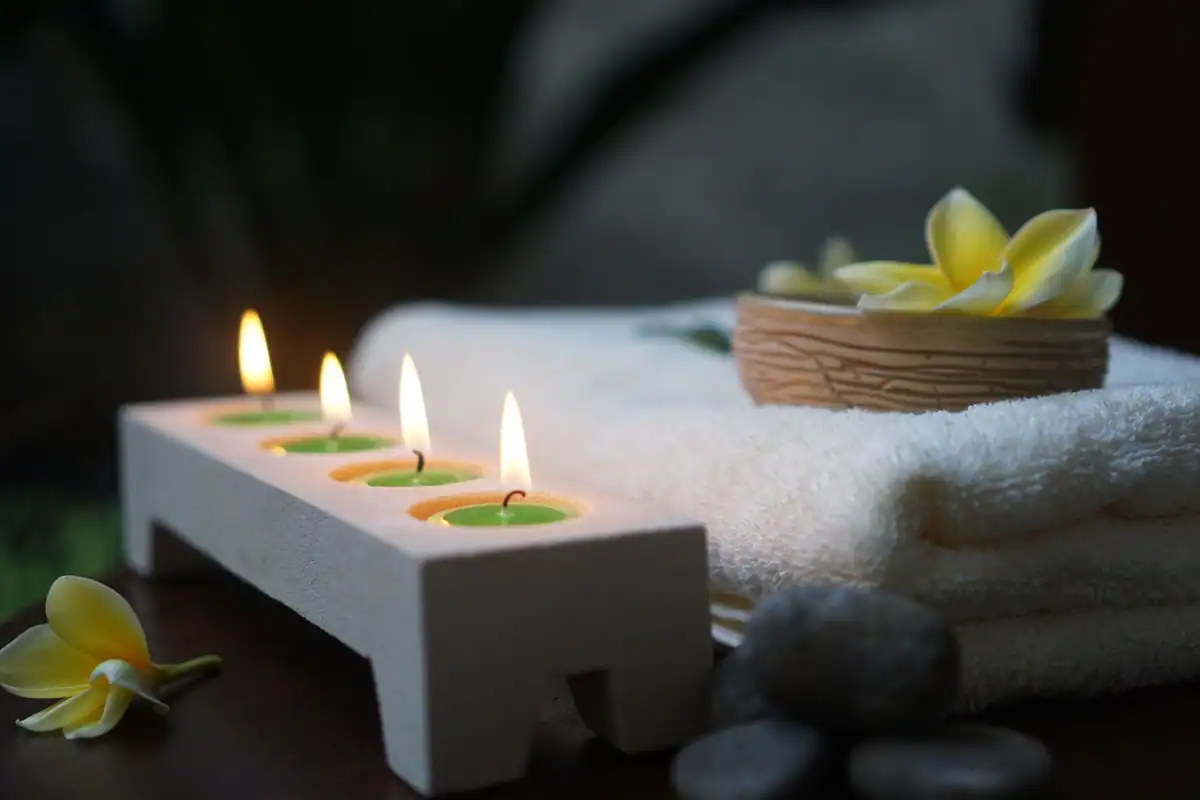 Spațiu de relaxare cu lumânări aprinse, prosoape albe, pietre și flori de frangipani