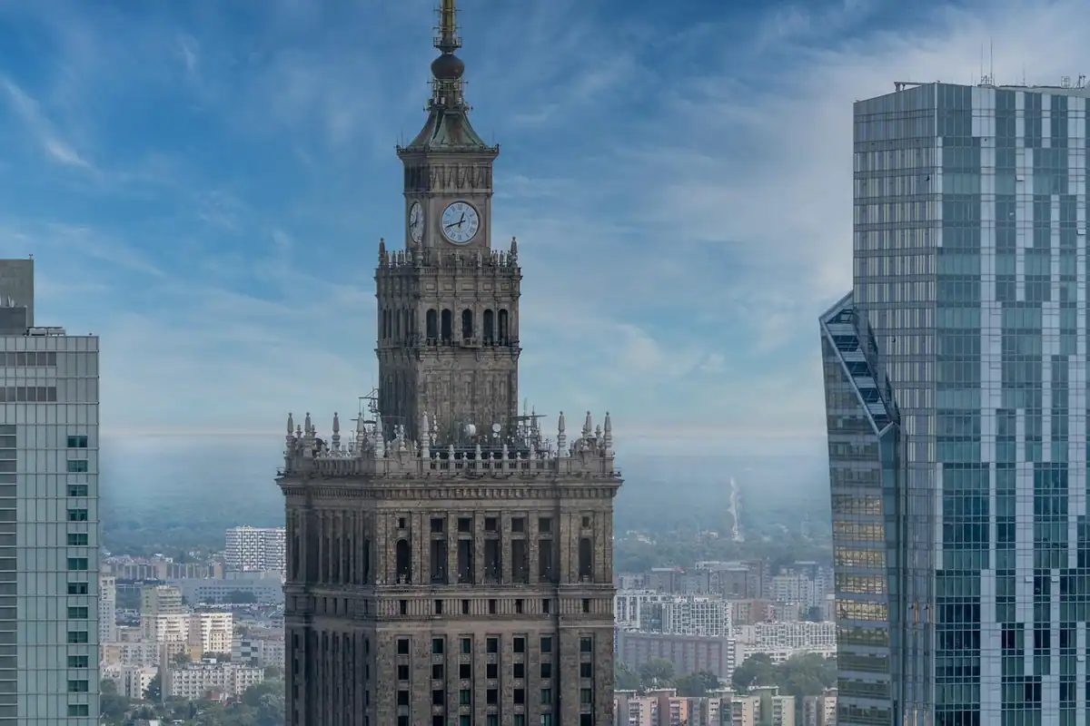 Clădiri monumentale de oraș cu turnuri și un palat cu fațadă elegantă, sub un cer cu nori