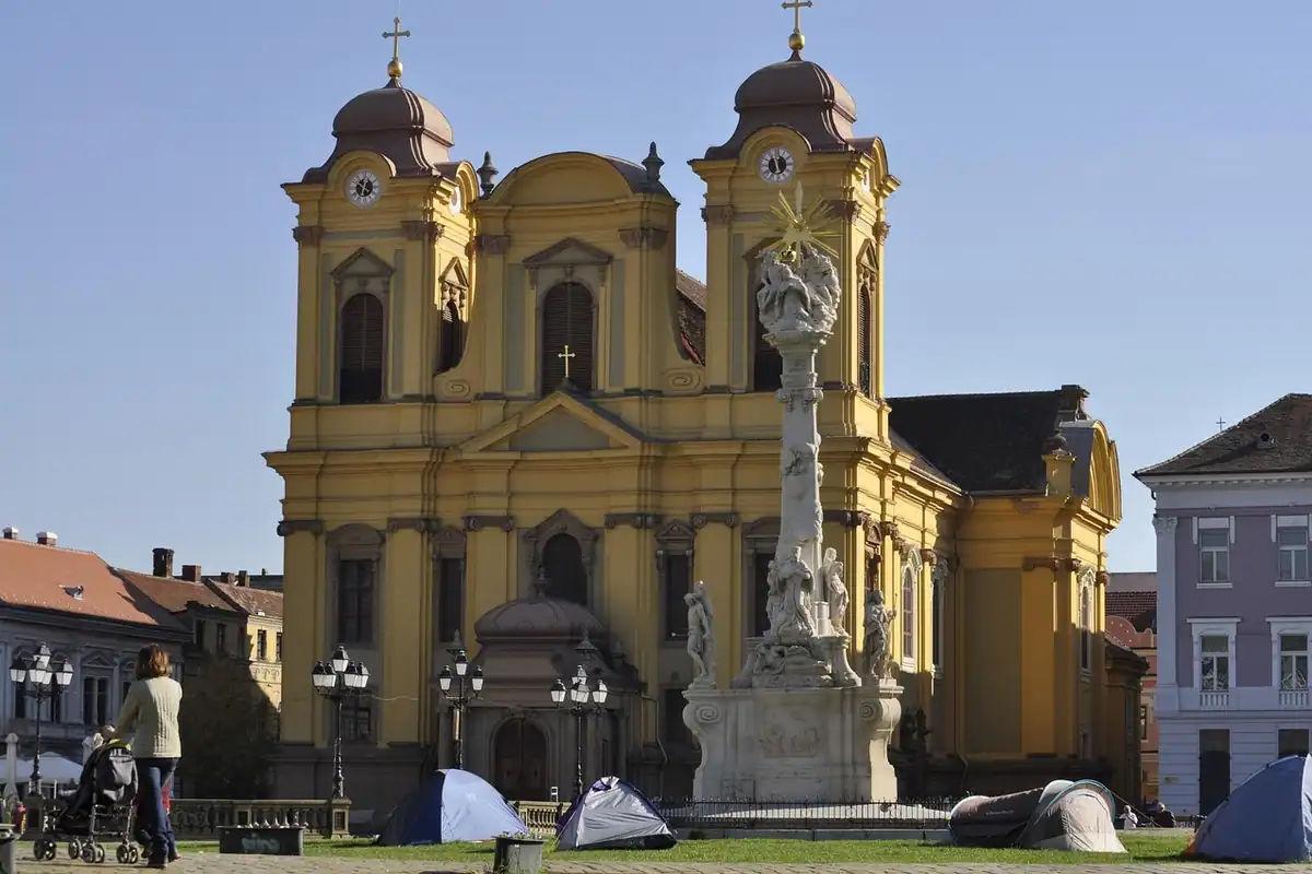 Piața Unirii din Timișoara, cu clădiri baroce galbene și o coloană în mijloc