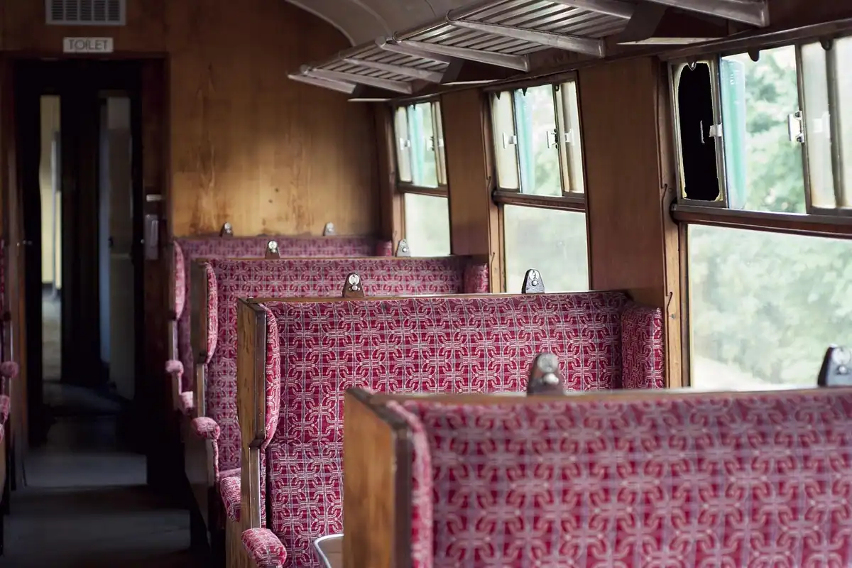 Compartiment de tren vechi cu bănci tapițate în roșu și ferestre mari