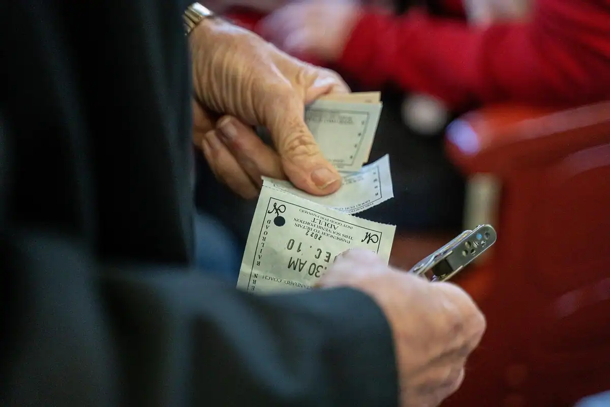 Bilet de tren de hârtie ținut în mână, de aproape, cu perforații de la controlor